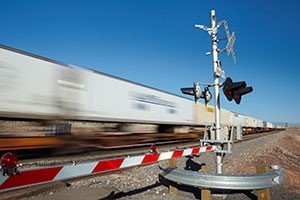 A pictures of a train passing by a railroad crossing